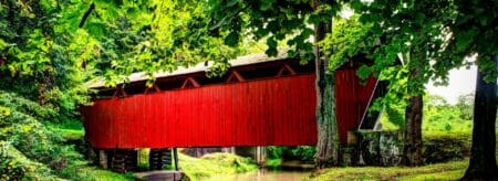bright red covered bridge surrounded by lush green foliage