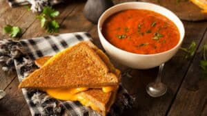 bowl of tomato soup and grilled cheese on the side