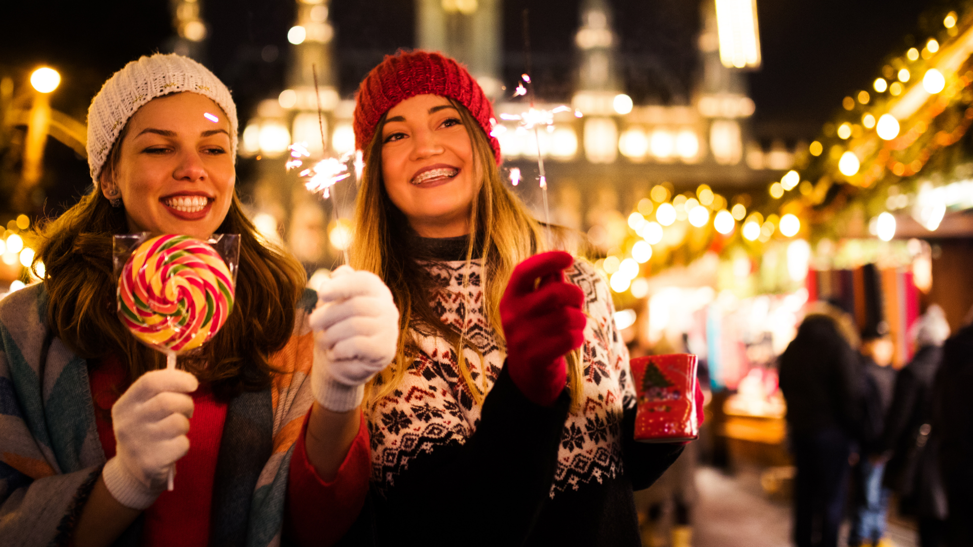 two ladies enjoying a christmas market at night with lights aglow