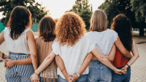 group of women standing outdoors with arms around each other holding hands