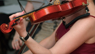 close up of woman holding violin in arm as she plays